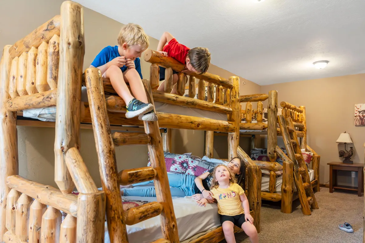 A playful bunk room with twin-over-full bunk beds, where children are seen playing and socializing. The room is bright and energetic, designed for fun as well as sleep.